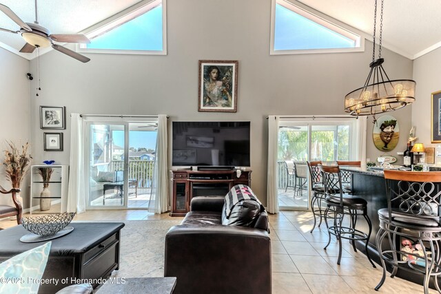 tiled living room with high vaulted ceiling, ornamental molding, and ceiling fan with notable chandelier