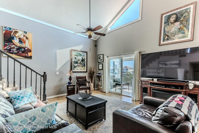 living area featuring stairs, ceiling fan, tile patterned flooring, and high vaulted ceiling
