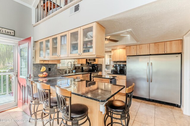 kitchen featuring appliances with stainless steel finishes, light tile patterned floors, a peninsula, light brown cabinets, and a breakfast bar