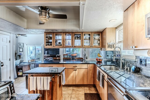 kitchen featuring a sink, appliances with stainless steel finishes, brown cabinetry, and a ceiling fan