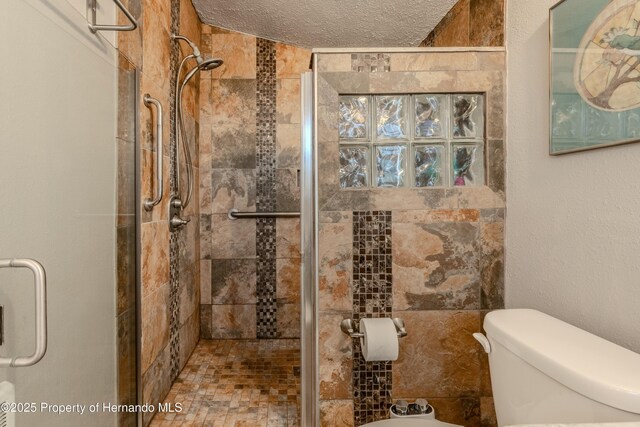 full bathroom featuring toilet, a textured ceiling, and a stall shower