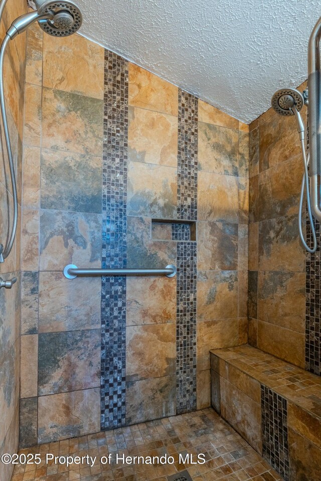bathroom with a textured ceiling and a stall shower