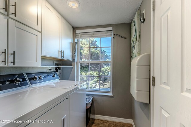 laundry room with baseboards, a textured ceiling, cabinet space, and independent washer and dryer