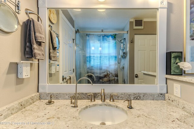 bathroom with vanity, visible vents, and a shower