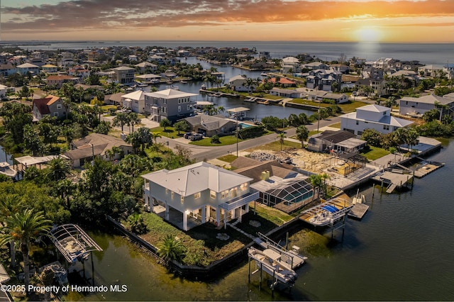 aerial view at dusk featuring a water view