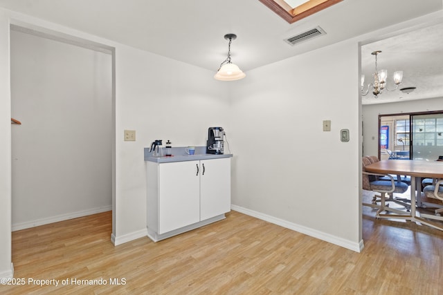 interior space featuring hanging light fixtures, white cabinetry, a chandelier, and light hardwood / wood-style floors