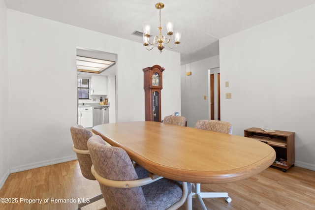 dining area with light hardwood / wood-style floors and a chandelier