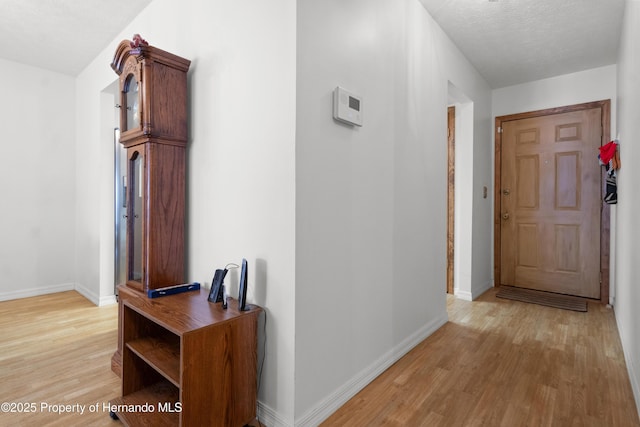 hallway with light hardwood / wood-style floors and a textured ceiling