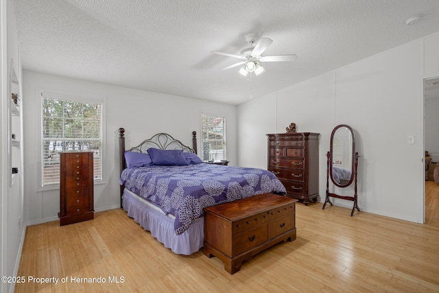 bedroom with multiple windows, ceiling fan, light hardwood / wood-style flooring, and a textured ceiling