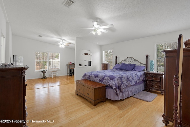 bedroom with ceiling fan, multiple windows, light hardwood / wood-style flooring, and a textured ceiling