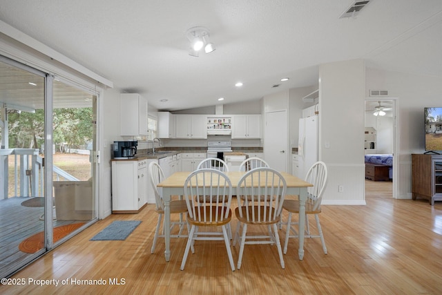 dining area featuring lofted ceiling, sink, and light wood-type flooring