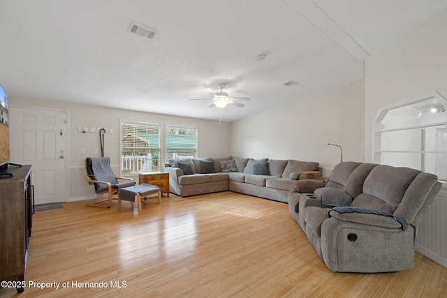 living room featuring ceiling fan, light hardwood / wood-style floors, and a textured ceiling