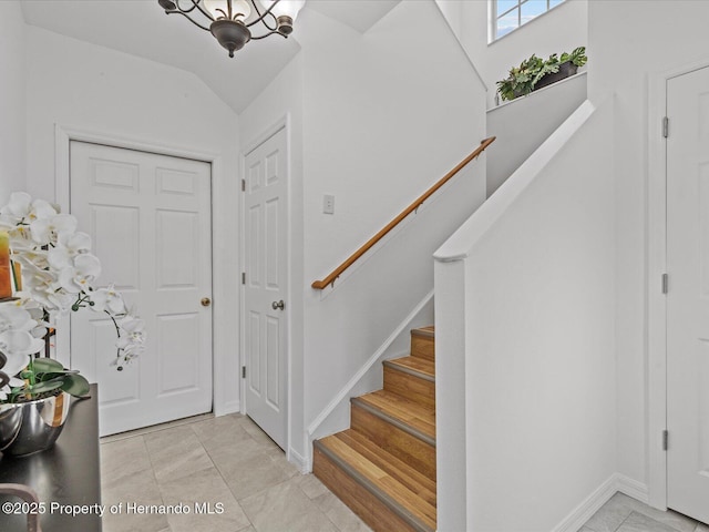 entryway with light tile patterned floors and a notable chandelier