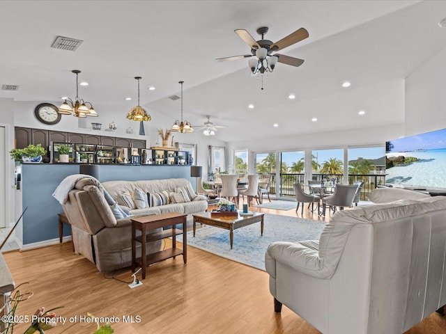 living room with lofted ceiling, ceiling fan with notable chandelier, and light hardwood / wood-style flooring