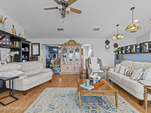 living room with ceiling fan with notable chandelier and light wood-type flooring