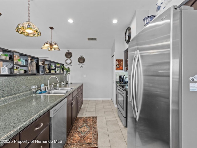 kitchen featuring dark brown cabinetry, sink, decorative light fixtures, light tile patterned floors, and stainless steel appliances