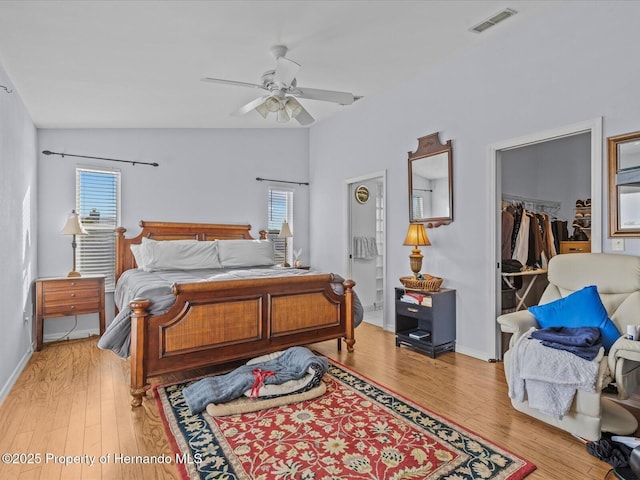 bedroom with lofted ceiling, light hardwood / wood-style flooring, ceiling fan, a walk in closet, and a closet