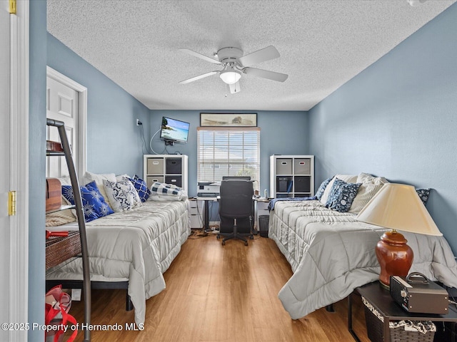 bedroom with hardwood / wood-style floors, a textured ceiling, and ceiling fan