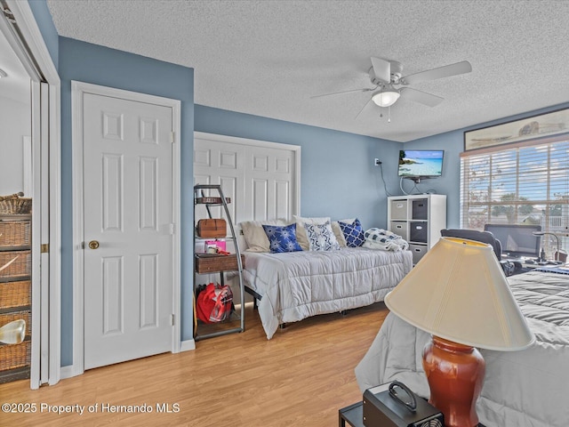 bedroom with ceiling fan, light hardwood / wood-style floors, and a textured ceiling