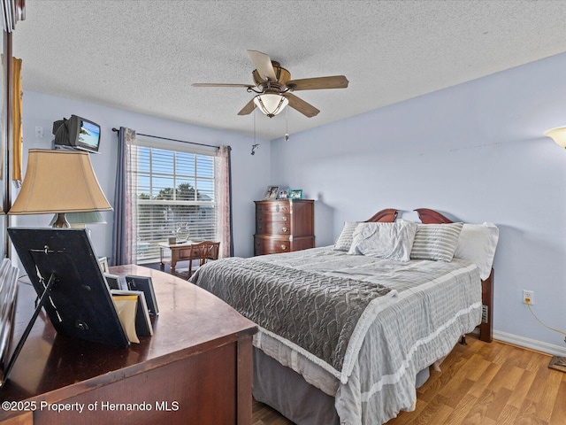 bedroom featuring hardwood / wood-style flooring, a textured ceiling, and ceiling fan