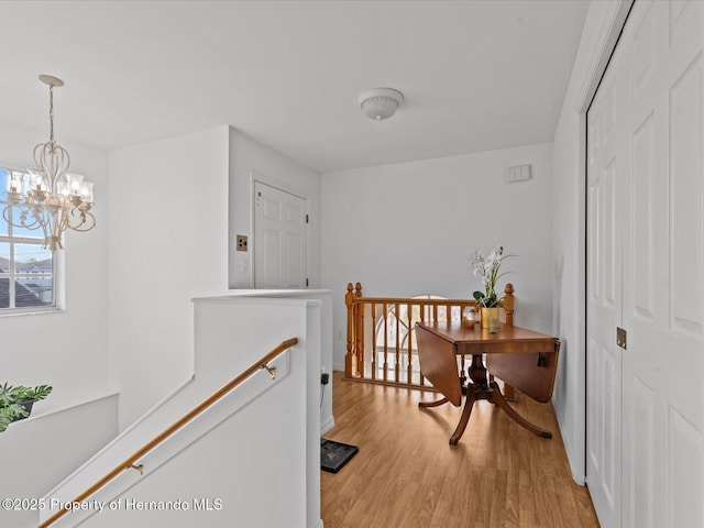 hallway with an inviting chandelier and light hardwood / wood-style flooring