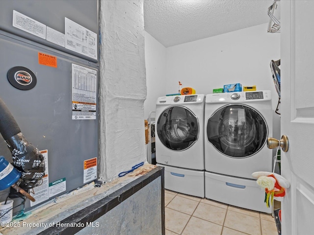 washroom featuring heating unit, separate washer and dryer, a textured ceiling, and light tile patterned floors