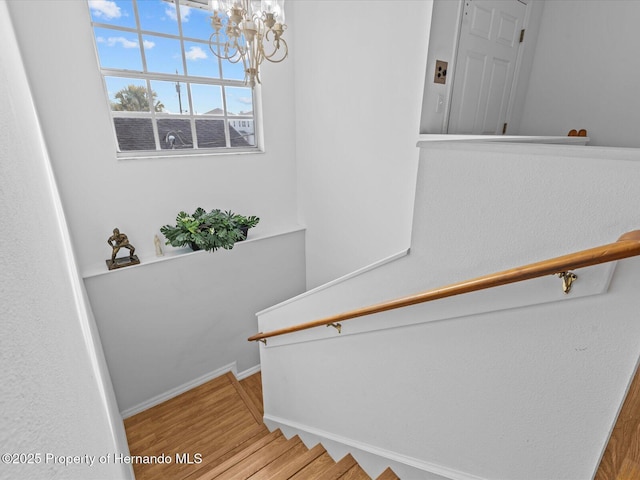 staircase featuring hardwood / wood-style floors and an inviting chandelier