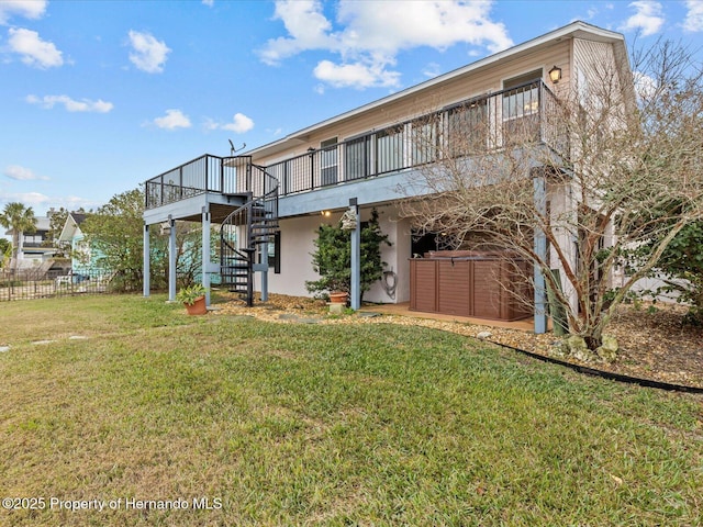 rear view of house featuring a wooden deck, a yard, and a jacuzzi