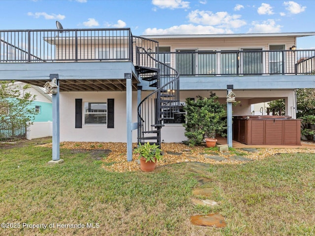 back of property with a yard, a hot tub, and a deck