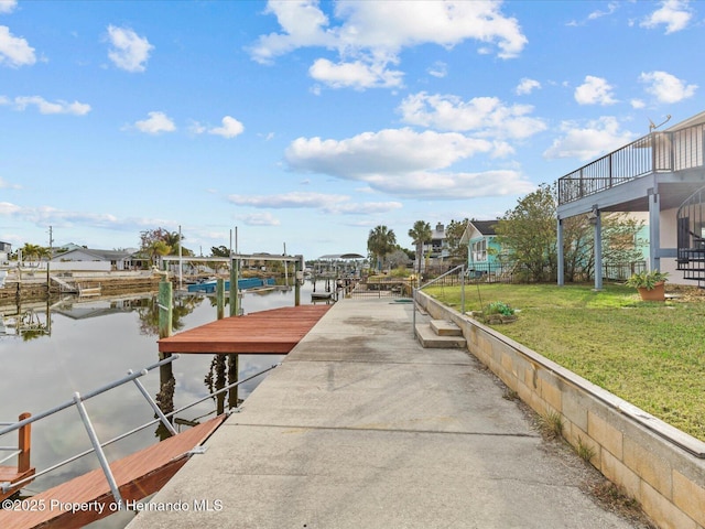 view of dock with a lawn and a water view