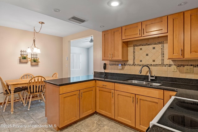 kitchen with pendant lighting, sink, backsplash, and kitchen peninsula