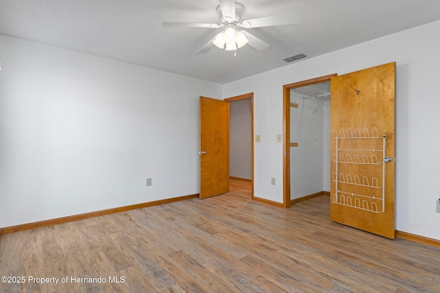 unfurnished bedroom featuring ceiling fan, wood-type flooring, and a textured ceiling