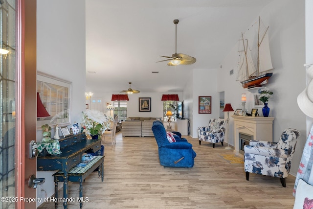 living room featuring ceiling fan, high vaulted ceiling, and light hardwood / wood-style floors