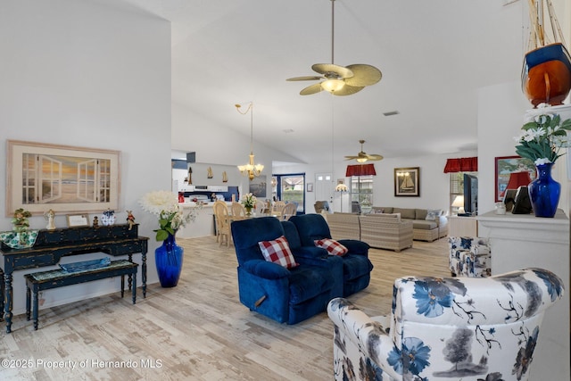 living room with high vaulted ceiling, ceiling fan with notable chandelier, and light hardwood / wood-style floors