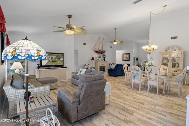 living room with high vaulted ceiling, ceiling fan with notable chandelier, and light hardwood / wood-style flooring