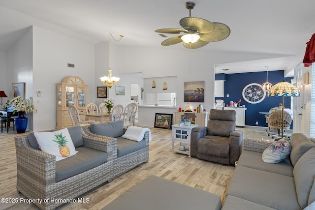 living room with ceiling fan with notable chandelier, light hardwood / wood-style flooring, and high vaulted ceiling