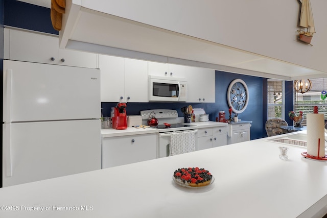 kitchen featuring white cabinetry, sink, white appliances, and a notable chandelier