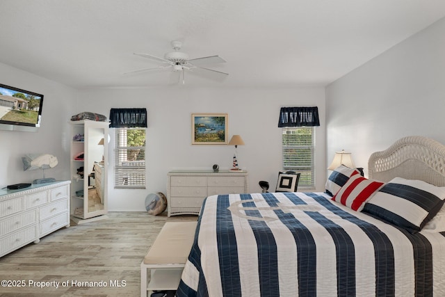 bedroom featuring ceiling fan, multiple windows, and light wood-type flooring