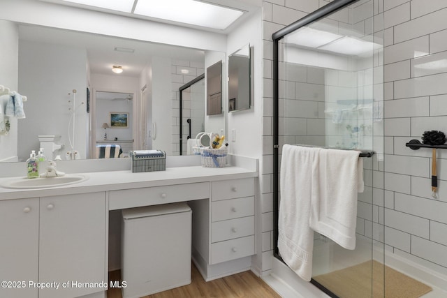 bathroom featuring vanity, wood-type flooring, and a shower with shower door