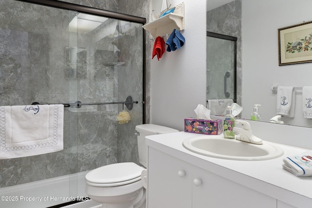 bathroom featuring toilet, vanity, and a shower with shower door