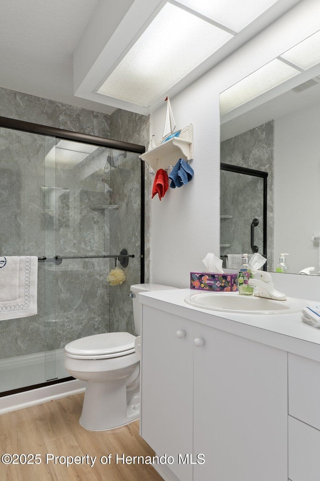 bathroom with hardwood / wood-style flooring, vanity, toilet, and walk in shower