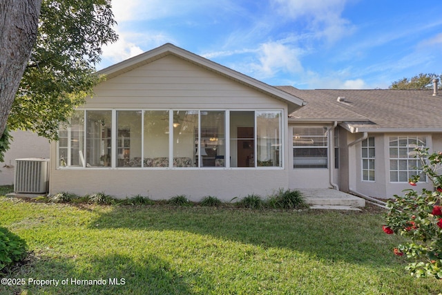 rear view of property featuring a sunroom, a yard, and cooling unit