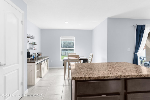 kitchen with light tile patterned flooring, dishwashing machine, and dark brown cabinetry