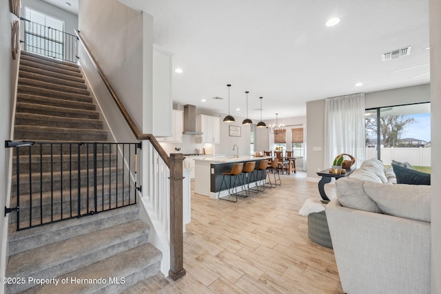 stairs featuring wood-type flooring, sink, and a chandelier