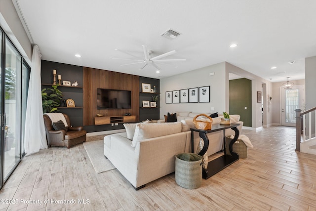 living room featuring ceiling fan with notable chandelier and light hardwood / wood-style floors