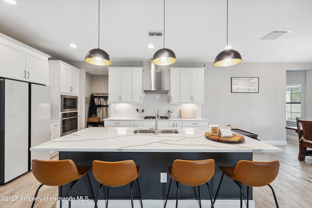 kitchen featuring decorative light fixtures, oven, an island with sink, and white fridge