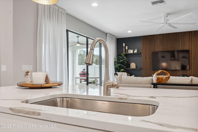 interior space with light stone countertops, sink, and ceiling fan