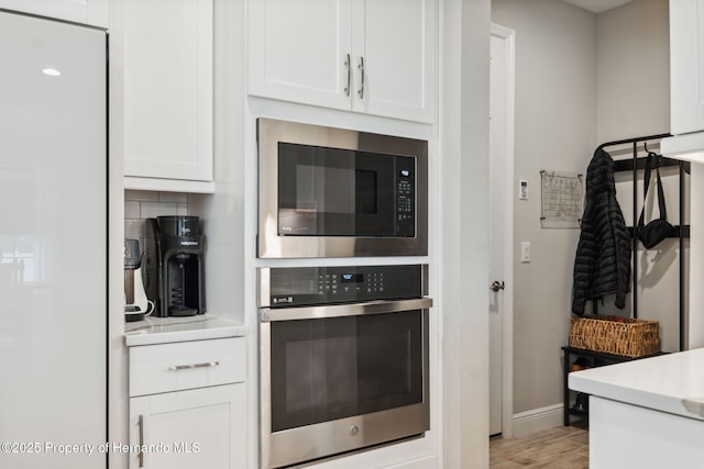 kitchen with white cabinetry, tasteful backsplash, light hardwood / wood-style floors, and appliances with stainless steel finishes