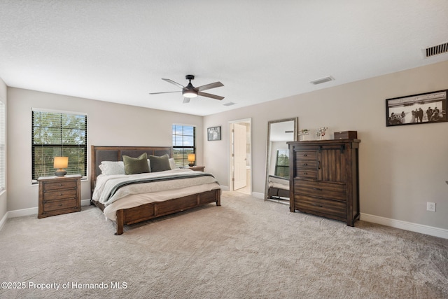 bedroom featuring ceiling fan, light colored carpet, and connected bathroom