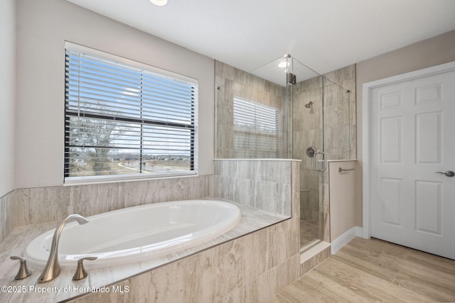 bathroom featuring wood-type flooring and shower with separate bathtub